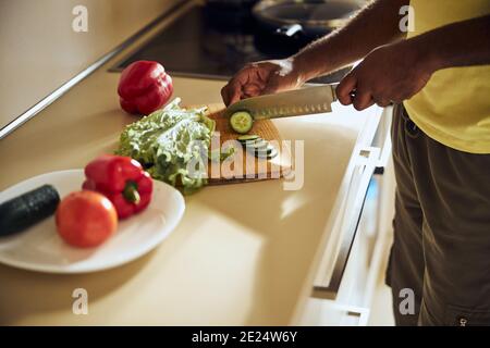 Person slicing the cucumbers on a cutting board Stock Photo