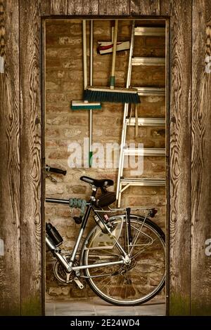 Retro styled image of a shed with a bicycle and garden tools inside Stock Photo