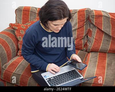 Middle aged woman (Dr Jayne Smith) logging on to UK Government website to register using Covid-19 home testing kit, Holt, Norfolk, January 2021 Stock Photo
