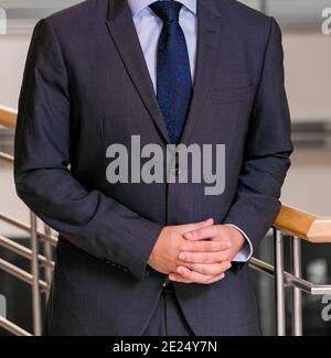 Mid-section of an elegantly dressed businessman in a suit standing with her hands crossed Stock Photo