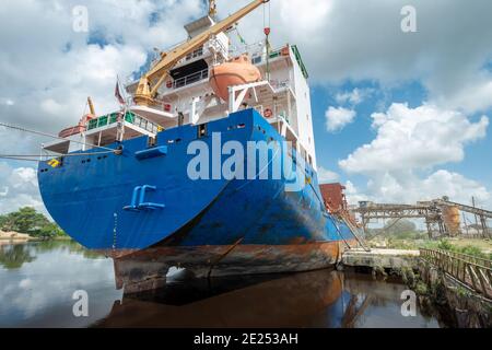 Ship moored at pier under loading operation. View from the aft stern prow with bollard and mooring lines. Stock Photo