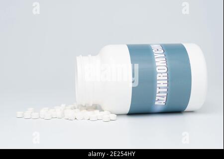 AZITROMYCIN antibiotic in white bottle packaging with scattered pills. Treatments for COVID-19. isolated on white background. Copy space. Close-up. Stock Photo