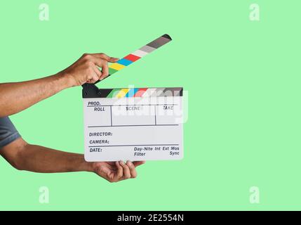 Hand holding a film clapboard slate or movie slate isolated on green background, with clipping path. Stock Photo