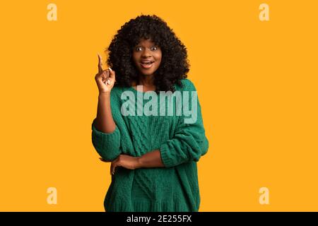 Cute black woman pointing finger up on yellow Stock Photo
