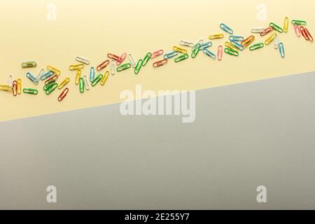 Abstract background in trendy colors of the year, yellow and gray, paper clips of different colors on backdrop Stock Photo