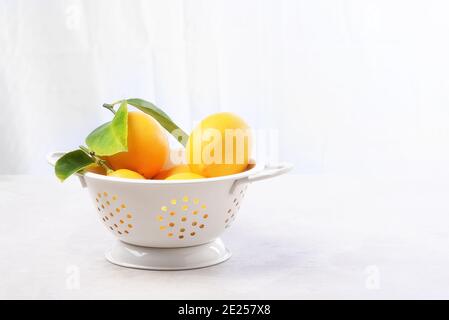 High key still life of lemons in a white colander. Horizontal with copy space. Stock Photo