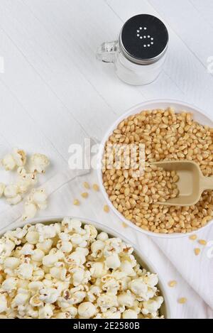 Flat Lay Making Popcorn. Bowls of popcorn and kernels on a white rustic table with copy space. Stock Photo