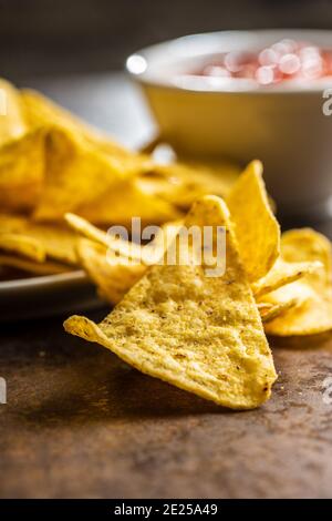 Tortilla chips and red tomato salsa dip. Mexican nacho chips on brown table. Stock Photo