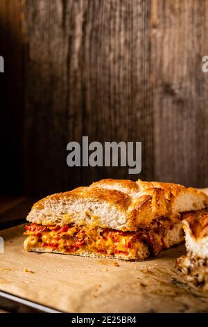 Grilled cheese sandwich with vegan cheese and red bell pepper in front of a rustic wooden background with copy space. Popular American fast food dish Stock Photo