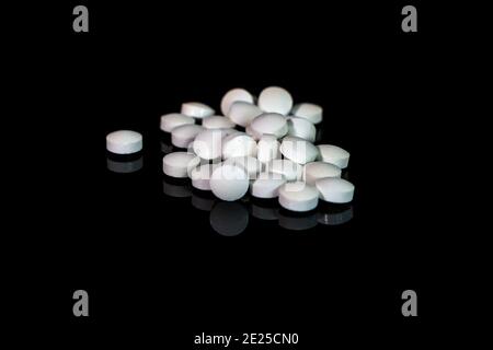 Vitamins and supplements pills isolated on black table with reflection. Stock Photo