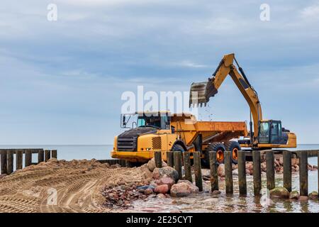 Industrial truck loader excavator moving sand and unloading it into a dumper truck Stock Photo