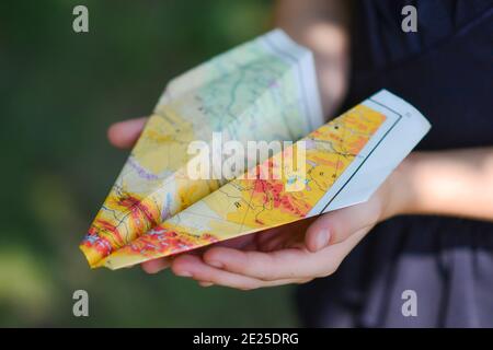 a paper airplane made from a geographical map. girl child holding a plane made of paper in her hand close-up. Stock Photo