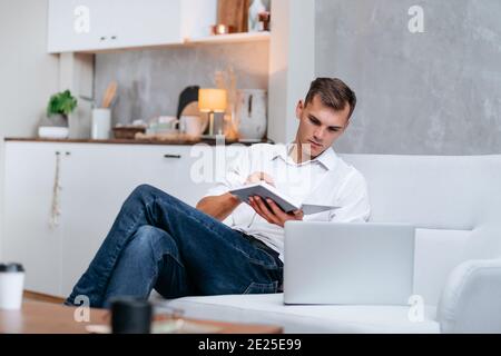young man taking notes sitting on the couch . Stock Photo