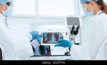 scientists in protective masks discussing the results of testing. Stock Photo
