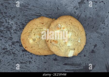 Two macadamia nut and white chocolate cookies on a gray mottled background. Stock Photo