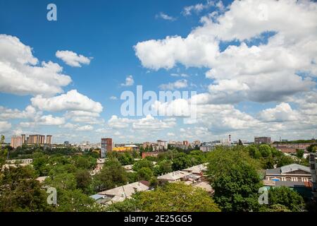 White clouds in the blue sky over the city and trees. Clear blue sky with plain white cloud with space for text background. Stock Photo