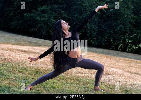 Young woman doing yoga in a garden in Eure, France Stock Photo