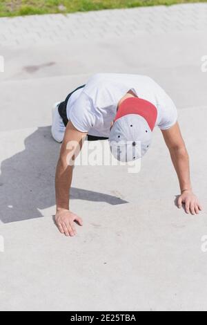 Vertical shot of a young male exercising doing pushups outdoors Stock Photo