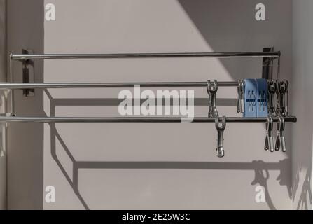 Empty clothes drying rack and Stainless steel clothes clips hanging on the wall in outside balcony of residential building. Air dryer rack for clothes Stock Photo