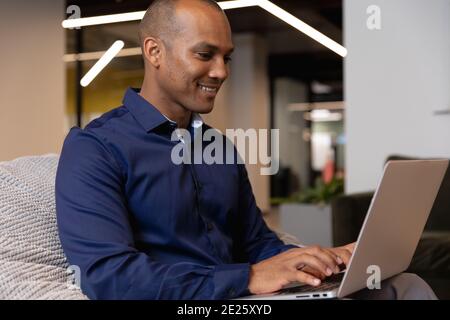 Mixed race businessman sitting using laptop in a modern office Stock Photo