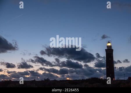 Lighthouse standing on the Dutch coast with a dramatic. and colorful dusk or dawn sky behind it. High quality photo Stock Photo
