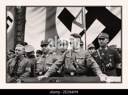 Archive 1930's Adolf Hitler in uniform wearing swastika armband at a political rally. with NSDAP members 1930s, Dortmund, Germany with large Swastika Flag as background Stock Photo