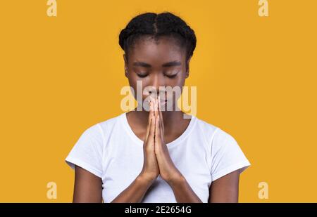 Peaceful African Lady Praying Standing With Eyes Closed In Studio Stock Photo