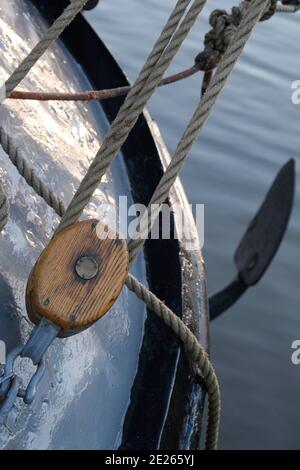 Brown wooden pulley with ropes on the bow of a ship. Focus on the wood of the pulley. Narrow depth of field Stock Photo