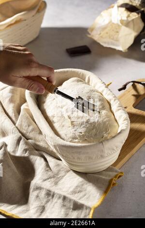 High angle shot of hand grating sourdough in a banneton basket Stock Photo