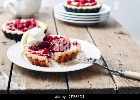 Baked mini tarts with raspberries on a rustic wooden table. Stock Photo