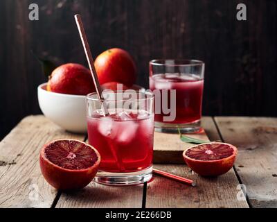 Red blood orange cocktail, citrus drink with ice cubes on a wooden background. Stock Photo