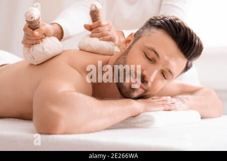 Handsome man enjoying herbal treatment at massage salon Stock Photo