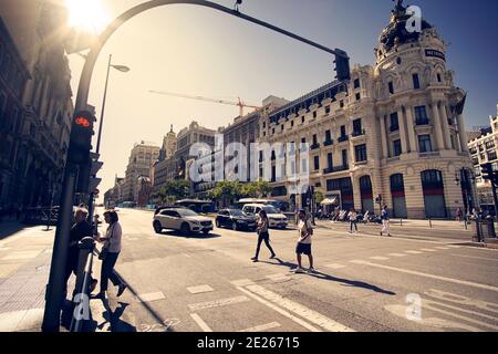 People crossing an avenue in Madrid Spain at traffic lights. View of the city streets.