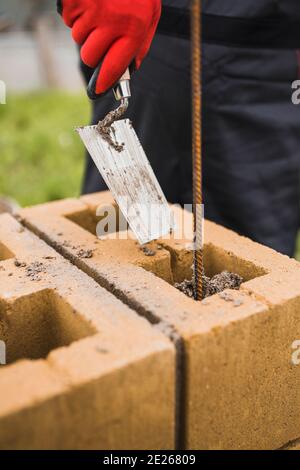 Construction of a stone pillar from concrete blocks - supporting structure of a brick fence Stock Photo