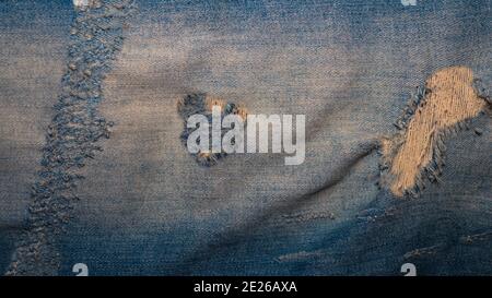 Denim fabric close-up, denim background, ripped blue jeans. Stock Photo