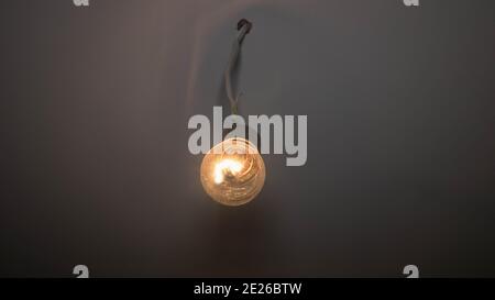 An incandescent lamp hangs on an old wire, a glowing lamp is covered in dust Stock Photo