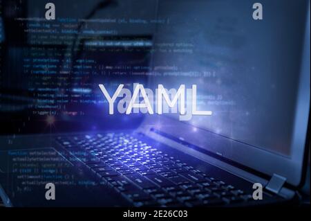 YAML inscription against laptop and code background. Technology concept. Stock Photo