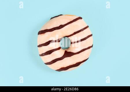 Donut glazed with white chocolate with brown stripes on light blue background Stock Photo