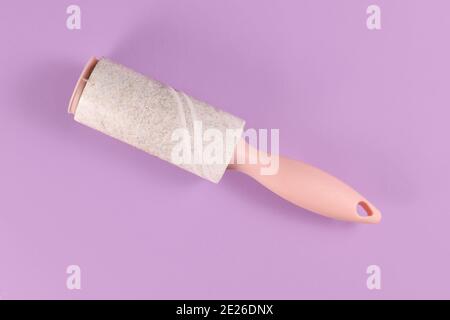 Used fluff roller for cleaning clothes on violet background Stock Photo