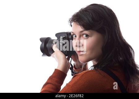 Side view of a female photographer holding a camera isolated on a white background for composites.  The model is posed to face a scenery or copy space Stock Photo