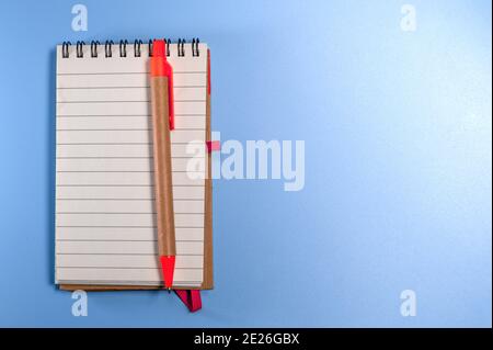 Notepad with eco pen on blue background. Sketchbook made of craft paper and a pen Stock Photo