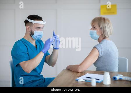 Senior Caucasian woman having covid-19 vaccine injection at hospital. Medical care and health services concept Stock Photo