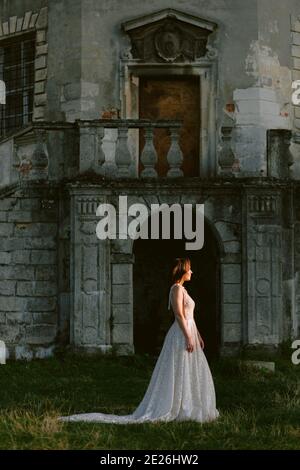 Stunning bride standing in front of old destroyed palace. Beautiful bride in profile. Wedding photo Stock Photo