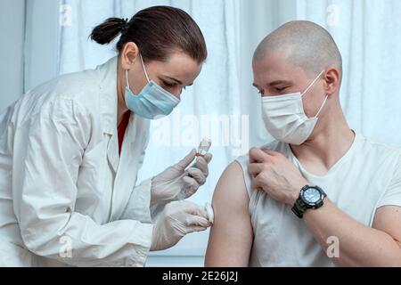 Female doctor injecting male patient with Covid19 antiviral vaccine. Mass vaccination and global immunization campaign. Close up. Stock Photo
