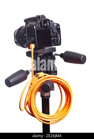 Digital photo camera on black tripod with orange rolled cable isolated on white background. Stock Photo