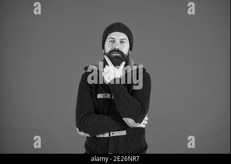 Winter menswear. Man bearded warm jumper and hat red background. Winter season menswear. Personal stylist. Warm and comfortable. Fashion menswear shop. Masculine clothes concept. Think and decide. Stock Photo