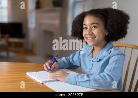 Ten year-old bi-racial girl doing homework at table Stock Photo