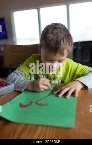 Little boy drawing volcano on green paper Stock Photo