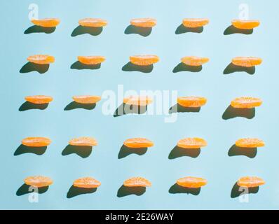 Creative pattern with  orange slices of tangerine  on vibrant  blue background. Minimal sunlit flat lay. Stock Photo