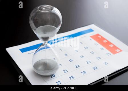 Time passing concept, time slipping away. Hourglass and the calendar Stock Photo